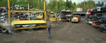 A man standing in front of a pile of cars