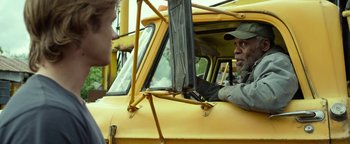 Movie still from “Monster Trucks” (2016), directed by Chris Wedge – A man sitting in the driver's seat of a yellow school bus; Close Up shot, Over the shoulder angle