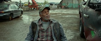 Movie still from “Monster Trucks” (2016), directed by Chris Wedge – An older man sitting on the ground in a field; Medium shot, Over the shoulder angle