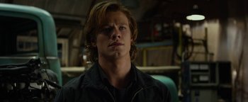 Movie still from “Monster Trucks” (2016), directed by Chris Wedge – A man with long brown hair wearing a black jacket; Close Up shot, Low angle