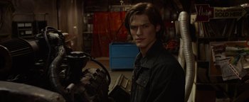 Movie still from “Monster Trucks” (2016), directed by Chris Wedge – A man in a garage holding a tool box; Medium shot, Over the shoulder angle