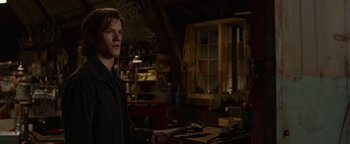 Movie still from “Monster Trucks” (2016), directed by Chris Wedge – A man standing in a room holding a pair of wrenches; Medium shot, Over the shoulder angle