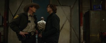 Movie still from “Monster Trucks” (2016), directed by Chris Wedge – Two men standing next to each other near a building; Medium shot, Over the shoulder angle