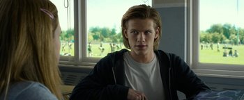 Movie still from “Monster Trucks” (2016), directed by Chris Wedge – A man with long blonde hair wearing a white t - shirt; Close Up shot, Over the shoulder angle