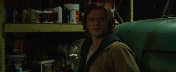 Movie still from “Monster Trucks” (2016), directed by Chris Wedge – A man with long brown hair standing in a room; Close Up shot, Over the shoulder angle