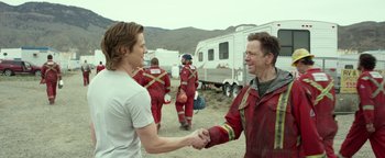 Movie still from “Monster Trucks” (2016), directed by Chris Wedge – Two men shaking hands in front of a trailer; Medium shot, Over the shoulder angle