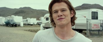 Movie still from “Monster Trucks” (2016), directed by Chris Wedge – A man with long brown hair is smiling for the camera; Close Up shot, Over the shoulder angle