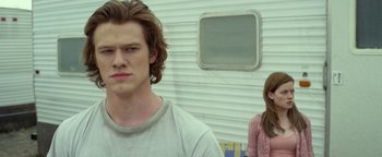 Movie still from “Monster Trucks” (2016), directed by Chris Wedge – A man and a woman standing next to each other in front of a trailer; Close Up shot, Over the shoulder angle