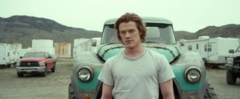 Movie still from “Monster Trucks” (2016), directed by Chris Wedge – A man standing in front of an old truck; Medium shot, Low angle