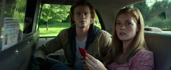 Movie still from “Monster Trucks” (2016), directed by Chris Wedge – A man and a woman sitting in the back of a car; Medium shot, Low angle