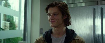 Movie still from “Monster Trucks” (2016), directed by Chris Wedge – A man with long brown hair and blue eyes smiling; Close Up shot, Low angle