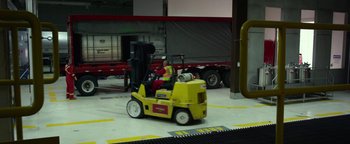 Movie still from “Monster Trucks” (2016), directed by Chris Wedge – A man driving a yellow forklift in a parking lot; Wide shot, Low angle