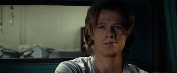 Movie still from “Monster Trucks” (2016), directed by Chris Wedge – A man with long brown hair sitting in front of a window; Close Up shot, Over the shoulder angle