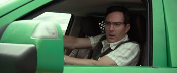 A man driving a green car in the back of the car