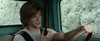 Movie still from “Monster Trucks” (2016), directed by Chris Wedge – A man holding a cell phone while sitting in a vehicle; Close Up shot, Over the shoulder angle