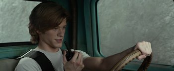 Movie still from “Monster Trucks” (2016), directed by Chris Wedge – A man holding a walkie talkie while sitting in a vehicle; Close Up shot, Over the shoulder angle