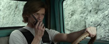 Movie still from “Monster Trucks” (2016), directed by Chris Wedge – A man sitting in a vehicle talking on a cell phone; Close Up shot, Low angle