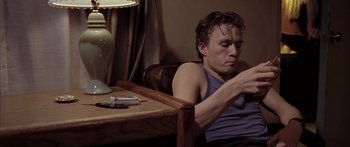 Movie still from “Monster's Ball” (2001), directed by Marc Forster – A man sitting at a table looking at his cell phone; Medium shot, Low angle