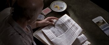 Movie still from “Monster's Ball” (2001), directed by Marc Forster – A person reading a newspaper at a table; Extreme Close Up shot, High angle