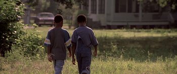 Movie still from “Monster's Ball” (2001), directed by Marc Forster – Two boys are walking in a field near a house; Medium shot, Over the shoulder angle