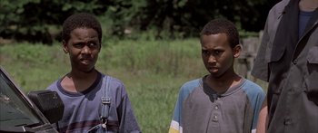 Movie still from “Monster's Ball” (2001), directed by Marc Forster – Two young men standing next to each other in front of a grassy area; Close Up shot, Over the shoulder angle
