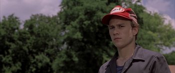 Movie still from “Monster's Ball” (2001), directed by Marc Forster – A young man wearing a baseball cap in front of a tree; Close Up shot, Low angle