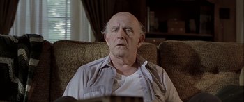 Movie still from “Monster's Ball” (2001), directed by Marc Forster – An older man sitting on a couch looking at the camera; Close Up shot, Low angle