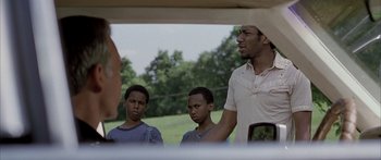 Movie still from “Monster's Ball” (2001), directed by Marc Forster – A group of young men standing next to each other in a field; Medium shot, Over the shoulder angle
