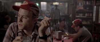 Movie still from “Monster's Ball” (2001), directed by Marc Forster – A man sitting in front of a group of people smoking a cigarette; Close Up shot, Over the shoulder angle