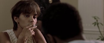 Movie still from “Monster's Ball” (2001), directed by Marc Forster – A woman smoking a cigarette while sitting on a couch; Close Up shot, Over the shoulder angle