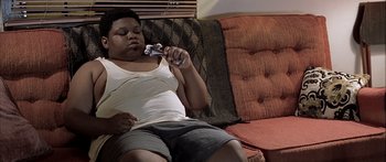 Movie still from “Monster's Ball” (2001), directed by Marc Forster – A woman sitting on a couch holding a remote control; Medium shot, High angle