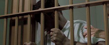 Movie still from “Monster's Ball” (2001), directed by Marc Forster – A man in white shirt behind a metal fence; Close Up shot, High angle