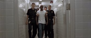 Movie still from “Monster's Ball” (2001), directed by Marc Forster – A group of police officers escorting a man in a white shirt; Wide shot, Low angle