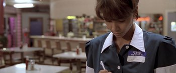 Movie still from “Monster's Ball” (2001), directed by Marc Forster – A woman holding a stylus in her hand while standing in front of a table; Close Up shot, High angle