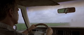 Movie still from “Monster's Ball” (2001), directed by Marc Forster – A person driving a car on a cloudy day; Close Up shot, Over the shoulder angle
