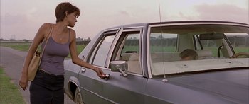 Movie still from “Monster's Ball” (2001), directed by Marc Forster – A young woman holding a remote control in her hand while standing next to the door of a car; Medium shot, Over the shoulder angle