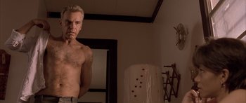 Movie still from “Monster's Ball” (2001), directed by Marc Forster – A man standing in front of a mirror in a room; Medium shot, Low angle