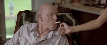 Movie still from “Monster's Ball” (2001), directed by Marc Forster – An older man is smoking a cigarette while being held by a woman; Close Up shot, High angle