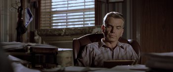 Movie still from “Monster's Ball” (2001), directed by Marc Forster – A man sitting at a desk in front of a window; Medium shot, Low angle