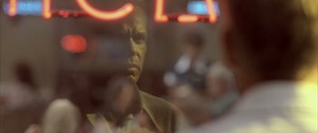 Movie still from “Monster's Ball” (2001), directed by Marc Forster – A man is seen through a window with a neon sign in the background; Extreme Close Up shot, Over the shoulder angle