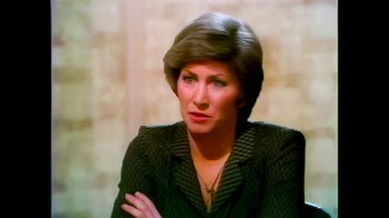 Movie still from “Moonage Daydream” (2022), directed by Brett Morgen – An older woman is sitting in front of a wall; Close Up shot, High angle