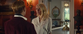 Movie still from “Mortdecai” (2015), directed by David Koepp – A woman standing next to a man in a room; Medium shot, Over the shoulder angle