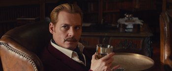 Movie still from “Mortdecai” (2015), directed by David Koepp – A man holding a glass in his right hand; Close Up shot, Low angle