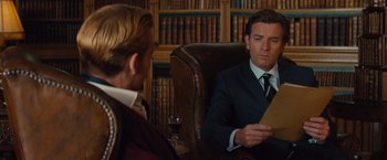 Movie still from “Mortdecai” (2015), directed by David Koepp – A man sitting in a leather chair in front of another man holding papers; Close Up shot, Over the shoulder angle