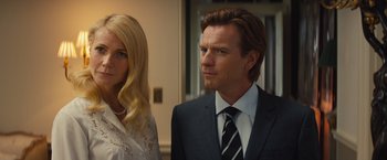 Movie still from “Mortdecai” (2015), directed by David Koepp – A man and a woman standing next to each other in a room; Close Up shot, Over the shoulder angle