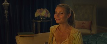 Movie still from “Mortdecai” (2015), directed by David Koepp – A woman sitting in front of a table with flowers in a vase; Close Up shot, Over the shoulder angle