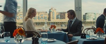 Movie still from “Mortdecai” (2015), directed by David Koepp – A man and a woman are sitting at a table; Medium shot, Over the shoulder angle