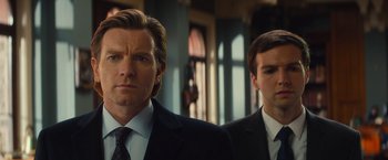 Movie still from “Mortdecai” (2015), directed by David Koepp – A man in a suit and tie standing next to another man in a suit and tie; Close Up shot, Low angle