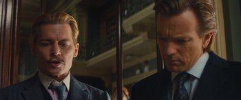 Movie still from “Mortdecai” (2015), directed by David Koepp – Two men in business suits standing next to each other; Close Up shot, Low angle