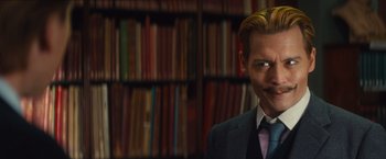 Movie still from “Mortdecai” (2015), directed by David Koepp – A man in a suit standing in front of bookshelves; Close Up shot, High angle
